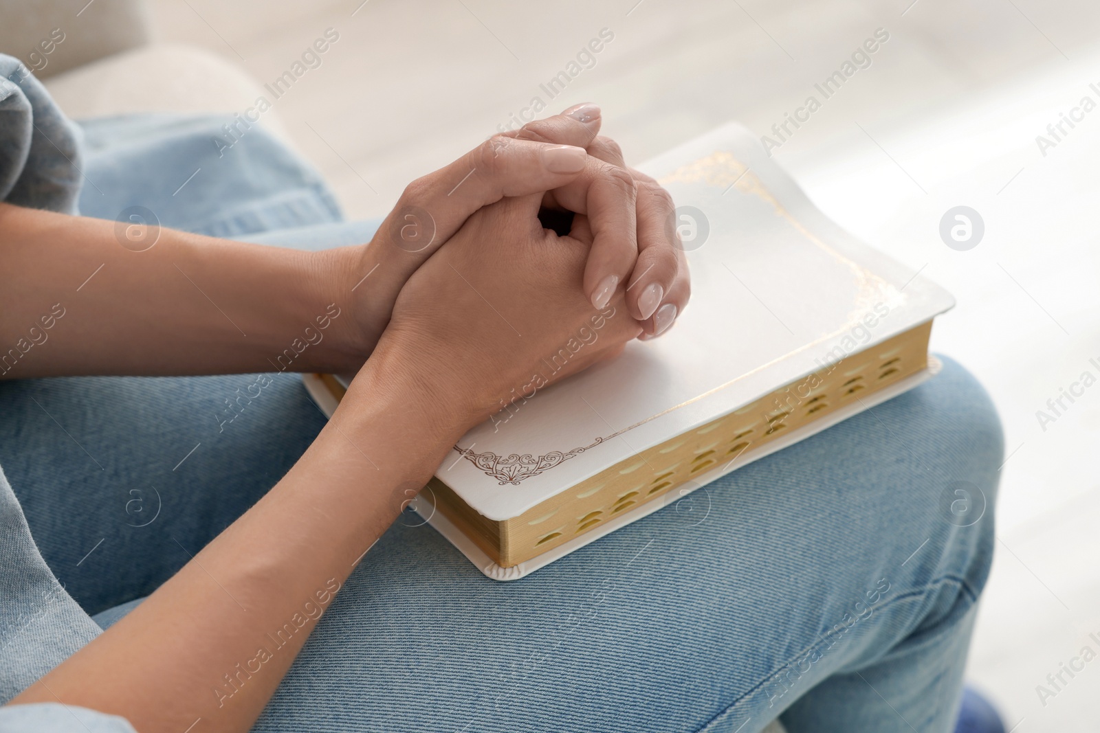 Photo of Religious woman with Bible praying indoors, closeup