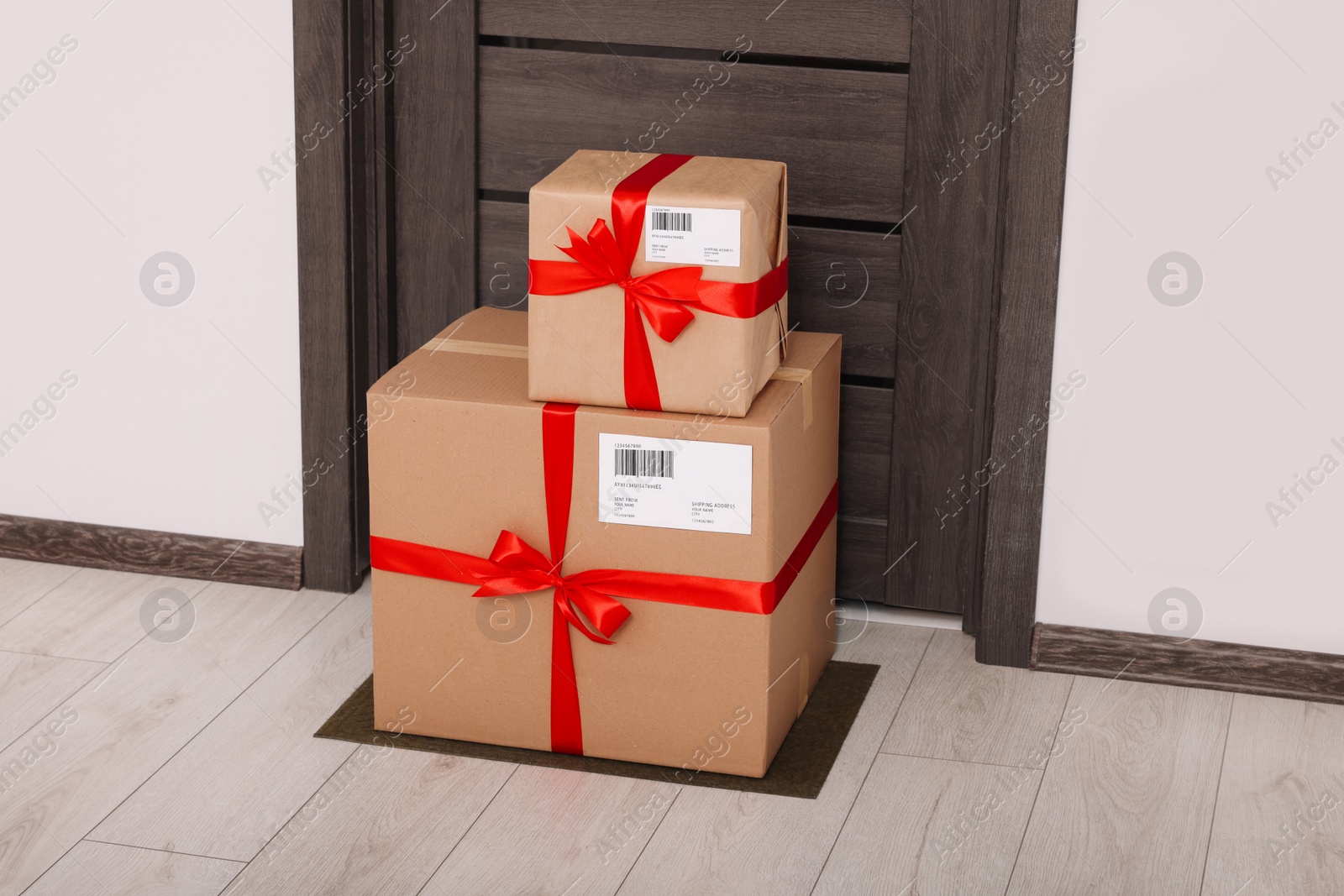 Photo of Christmas gift boxes on floor near door. Sending present by mail