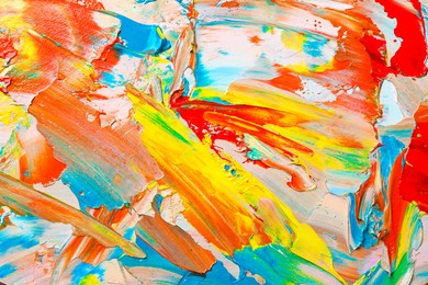 Closeup view of artist's palette with mixed bright paints as background