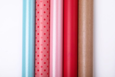 Rolls of different bright wrapping paper on white background, top view