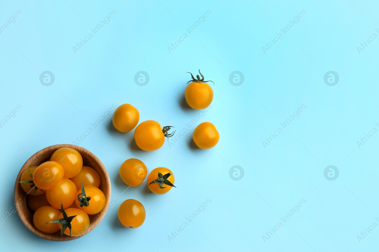 Photo of Yellow tomatoes on light blue background, flat lay. Space for text