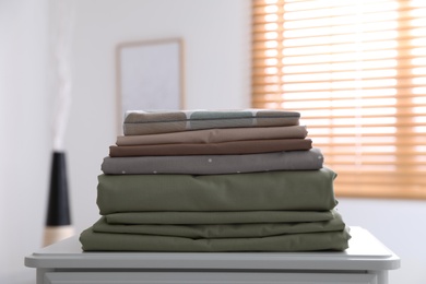 New clean folded bed linens on table indoors