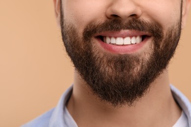 Man with clean teeth smiling on beige background, closeup. Space for text