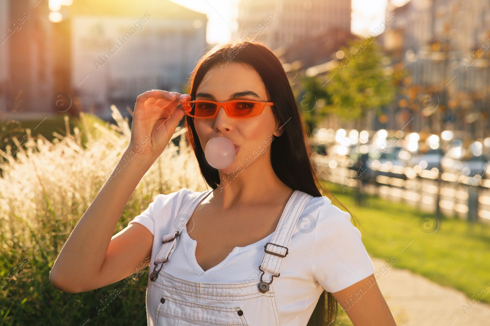 Photo of Beautiful woman in sunglasses blowing gum outdoors