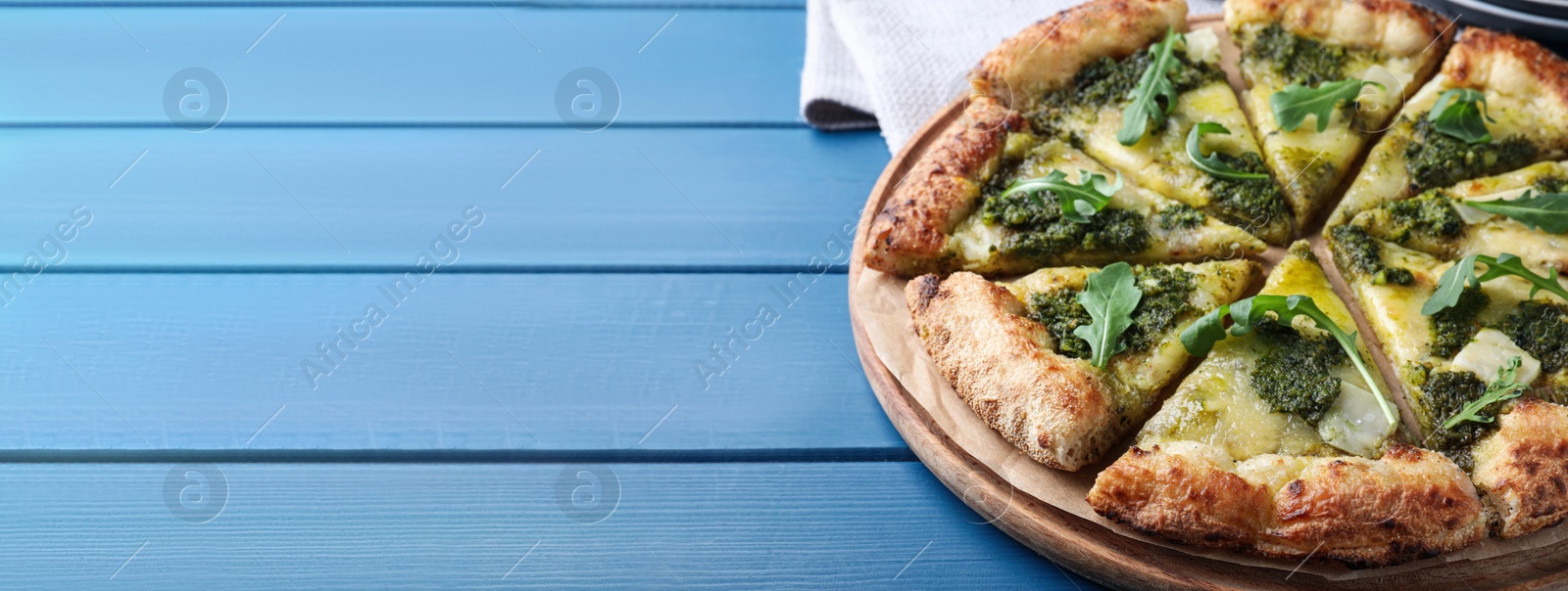 Image of Delicious pizza with pesto, cheese and arugula on blue wooden table, space for text. Banner design