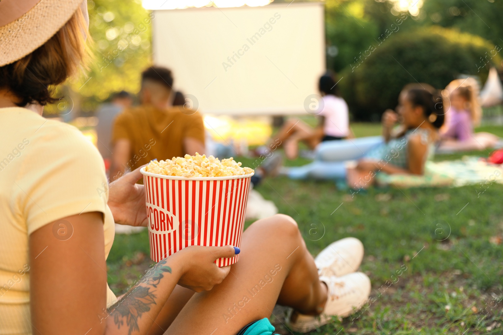 Photo of Young woman with popcorn watching movie in open air cinema, closeup. Space for text