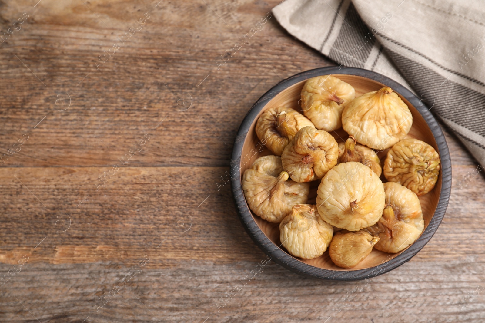 Photo of Tasty dried figs in plate on wooden table, top view. Space for text