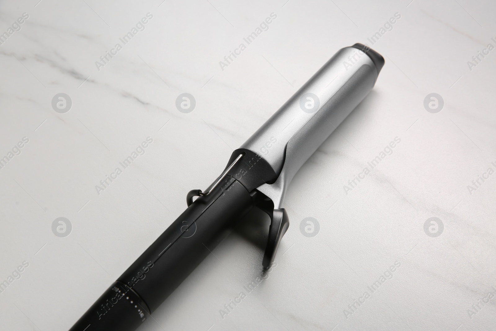 Photo of Hair curling iron on white marble background