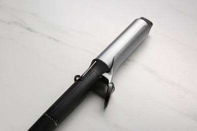 Hair curling iron on white marble background
