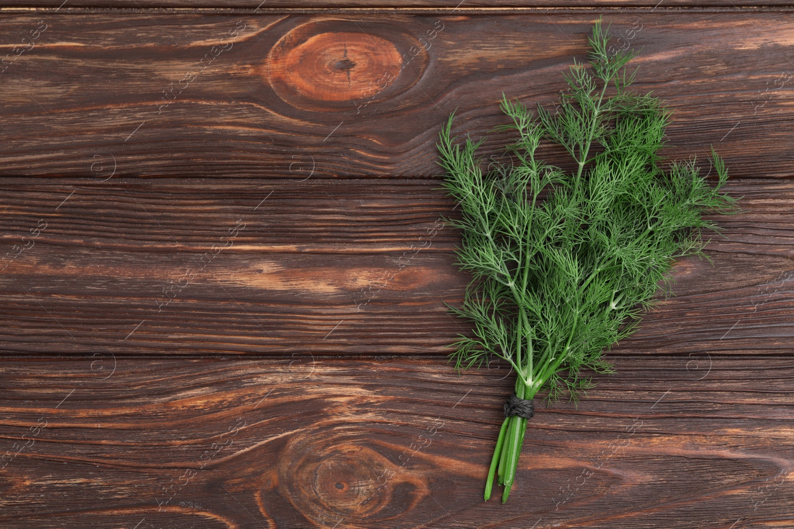 Photo of Bunch of fresh dill on wooden table, top view. Space for text
