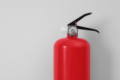 Photo of Fire extinguisher near light grey wall, space for text