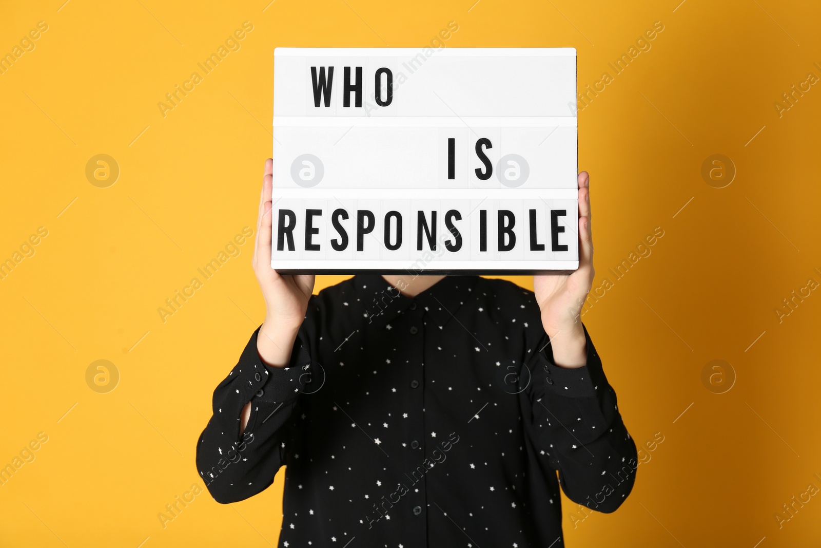 Photo of Woman holding light box with phrase Who Is Responsible on orange background