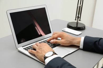 Photo of Man in office wear using laptop at table indoors