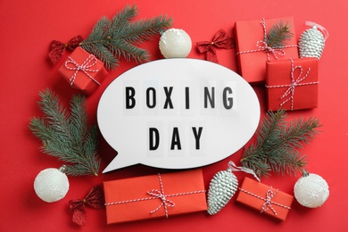 Photo of Speech bubble with phrase BOXING DAY and Christmas decorations on red background, flat lay