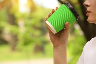 Photo of Woman with takeaway coffee cup in park, closeup