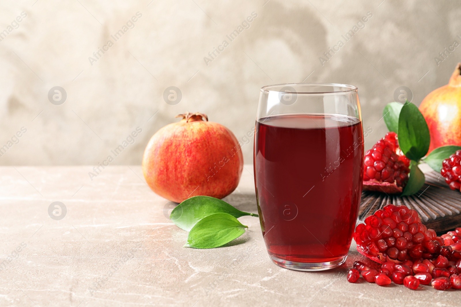 Photo of Composition with glass of fresh pomegranate juice on table. Space for text