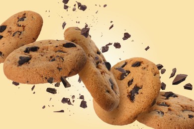 Image of Tasty chocolate chip cookies falling on pale gold background