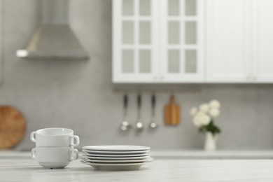 Photo of Clean dishware on white table in kitchen, space for text