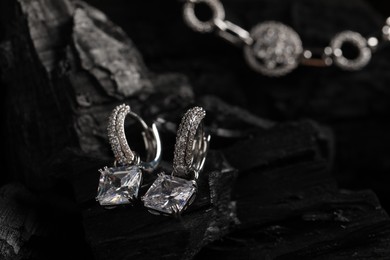 Photo of Luxury jewelry. Stylish presentation of elegant earrings on coal, closeup