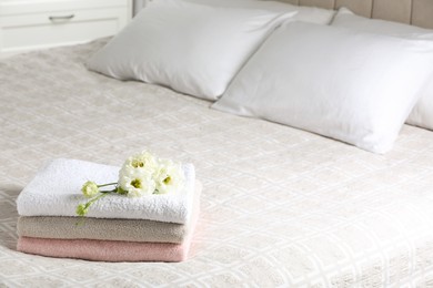 Photo of Terry towels with beautiful flowers on bed indoors, space for text