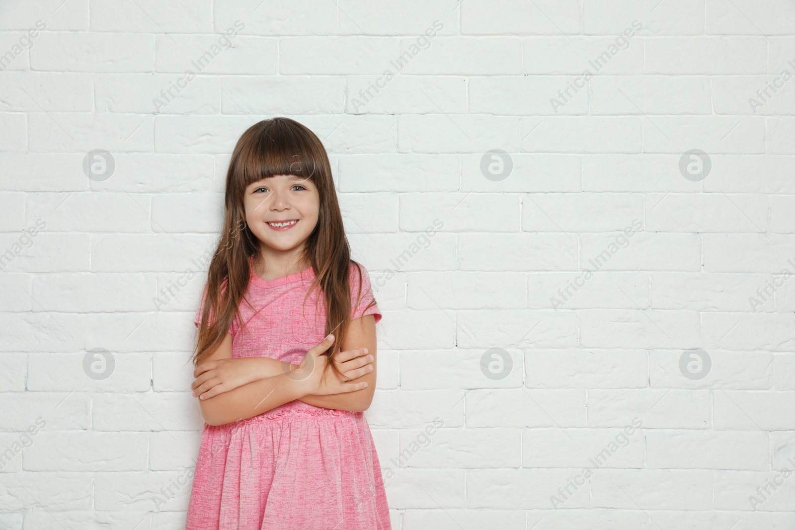 Photo of Portrait of cute little girl against brick wall. Space for text