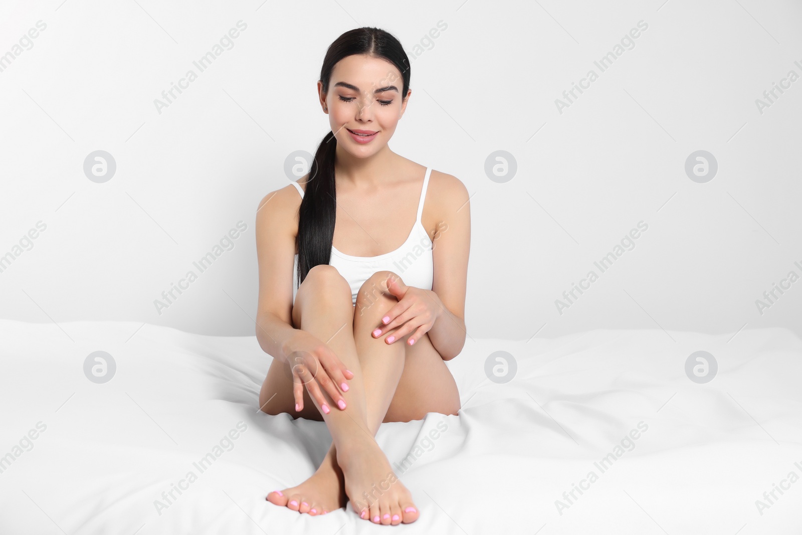 Photo of Young woman showing smooth skin after epilation on bed