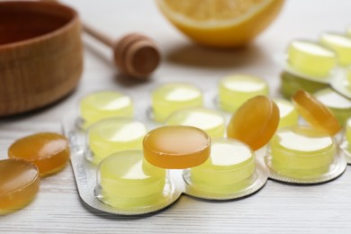 Many cough drops on white wooden table, closeup