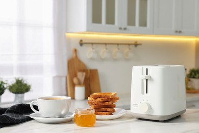 Photo of Breakfast served in kitchen. Toaster, crunchy bread, honey and coffee on white table
