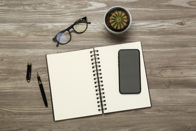 Photo of Flat lay composition with notebook and smartphone on wooden table