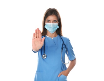 Photo of Doctor in protective mask showing stop gesture on white background. Prevent spreading of coronavirus