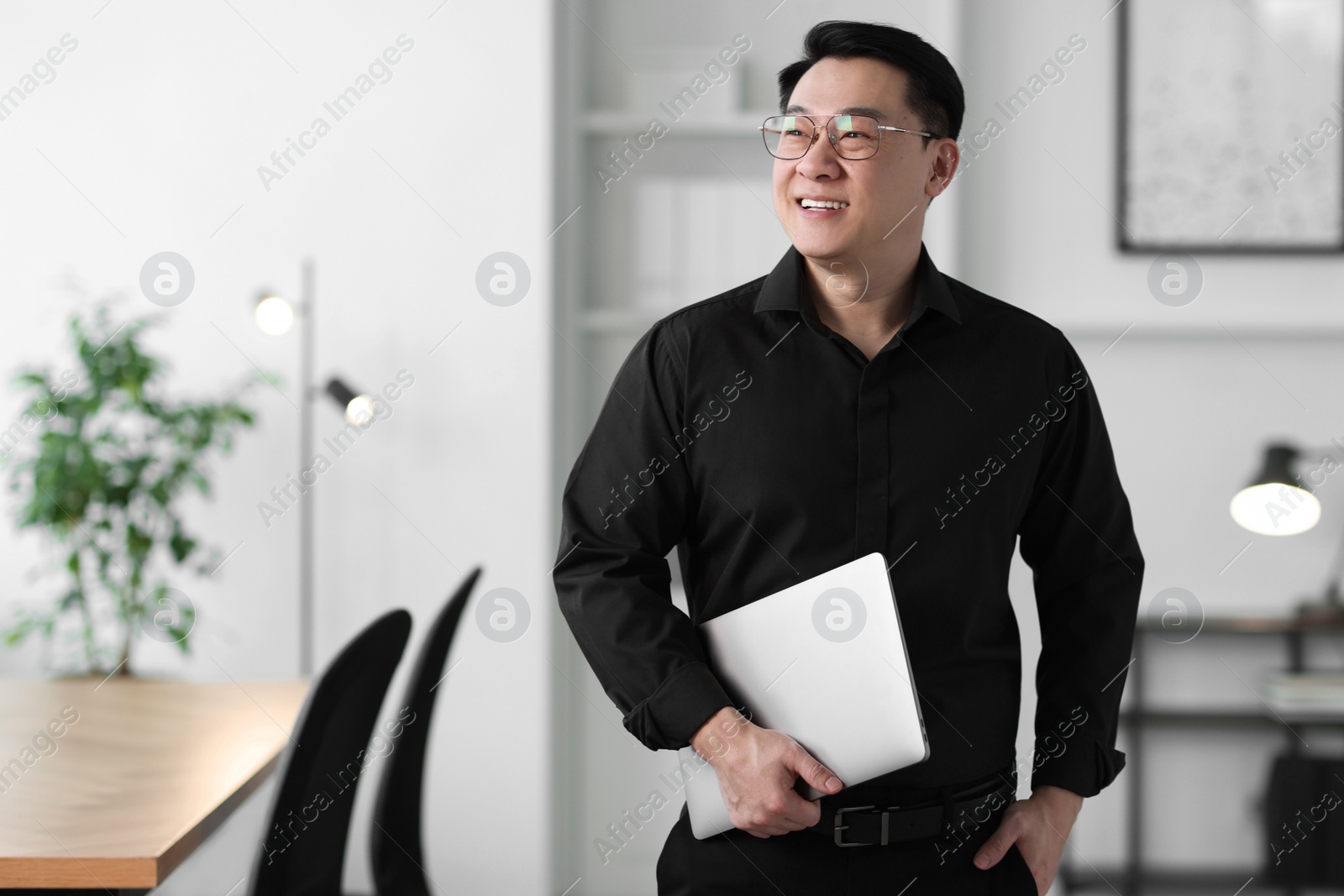 Photo of Portrait of smiling businessman with laptop in office. Space for text