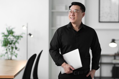 Photo of Portrait of smiling businessman with laptop in office. Space for text