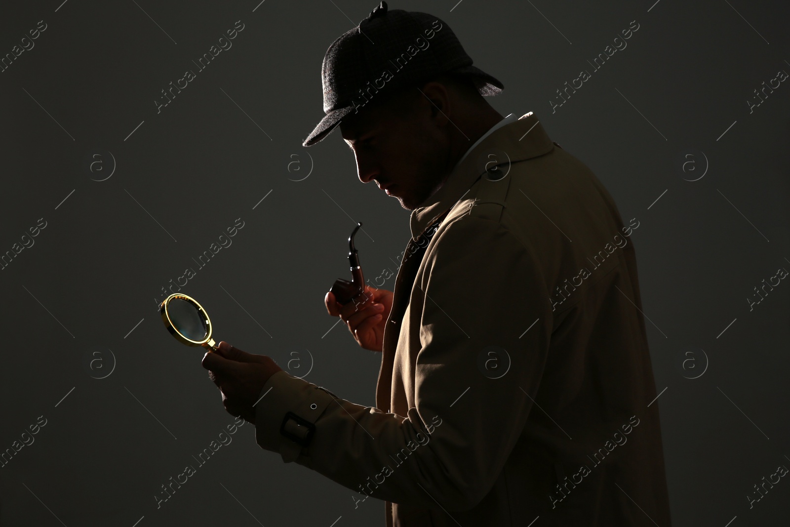 Photo of Old fashioned detective with smoking pipe and magnifying glass on dark background