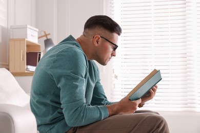 Photo of Man with poor posture reading book at home