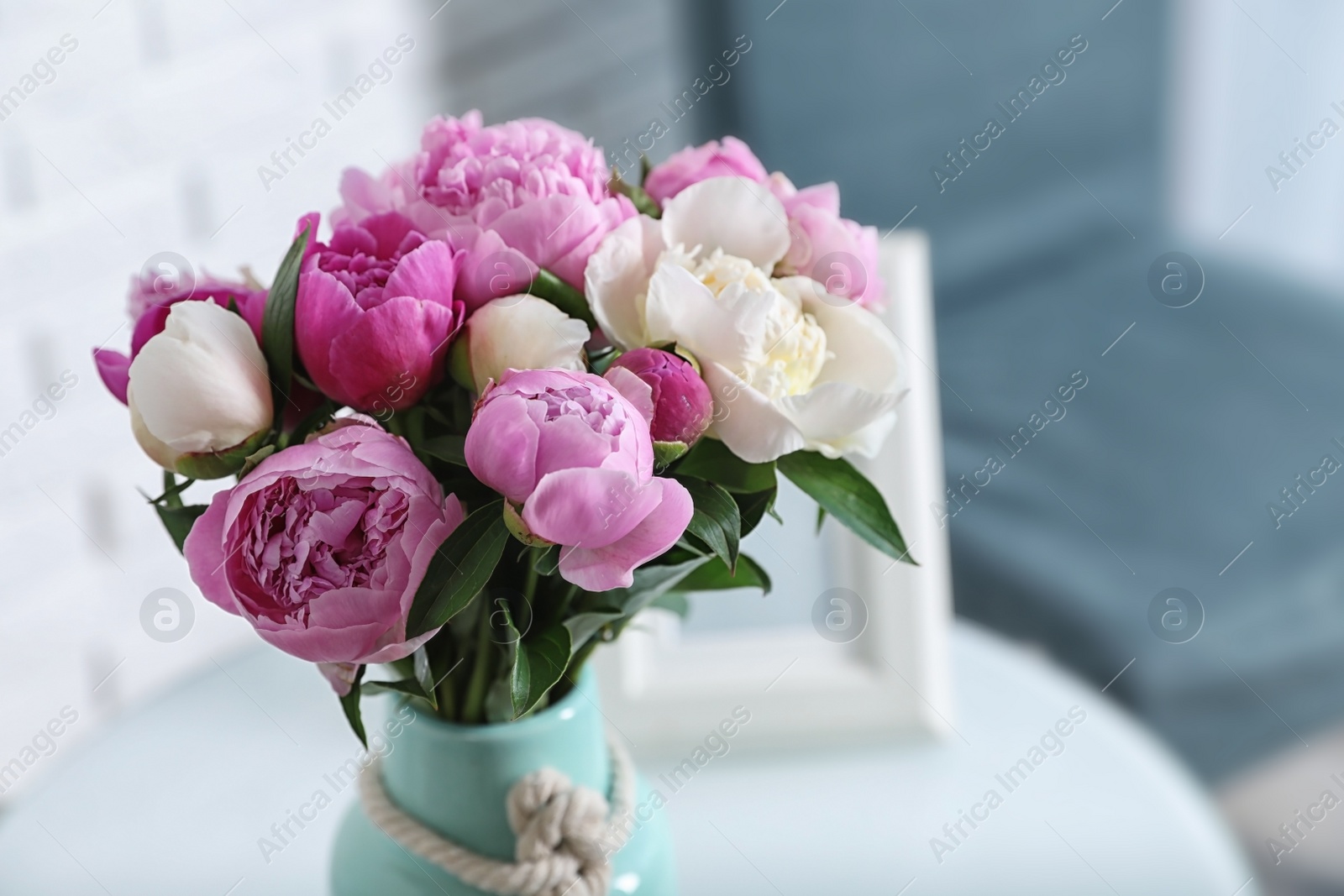 Photo of Vase with bouquet of beautiful peonies on table in room, space for text