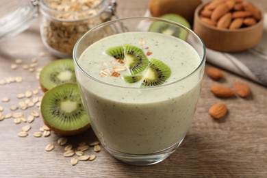 Photo of Glass of tasty kiwi smoothie with oatmeal on wooden table