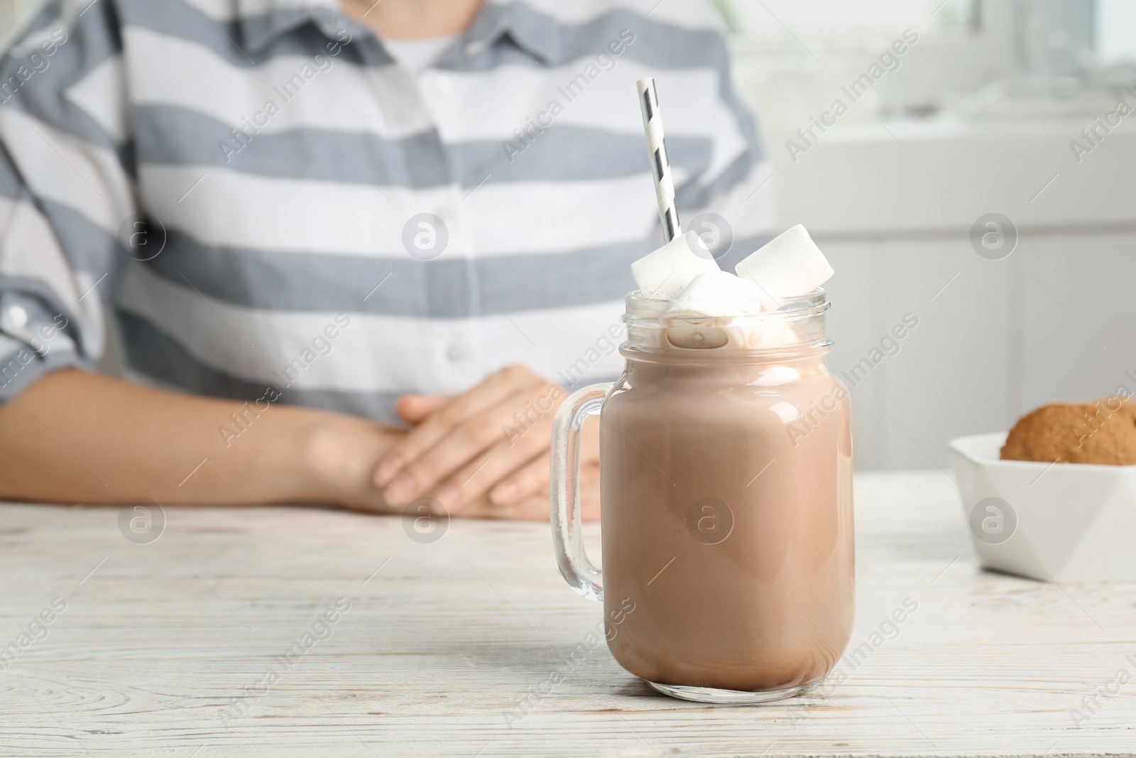 Photo of Young woman with delicious hot cocoa drink at table