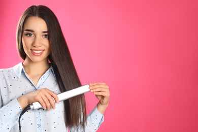 Happy woman using hair iron on color background. Space for text