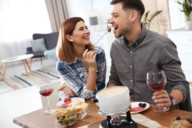 Photo of Happy couple enjoying fondue dinner at home