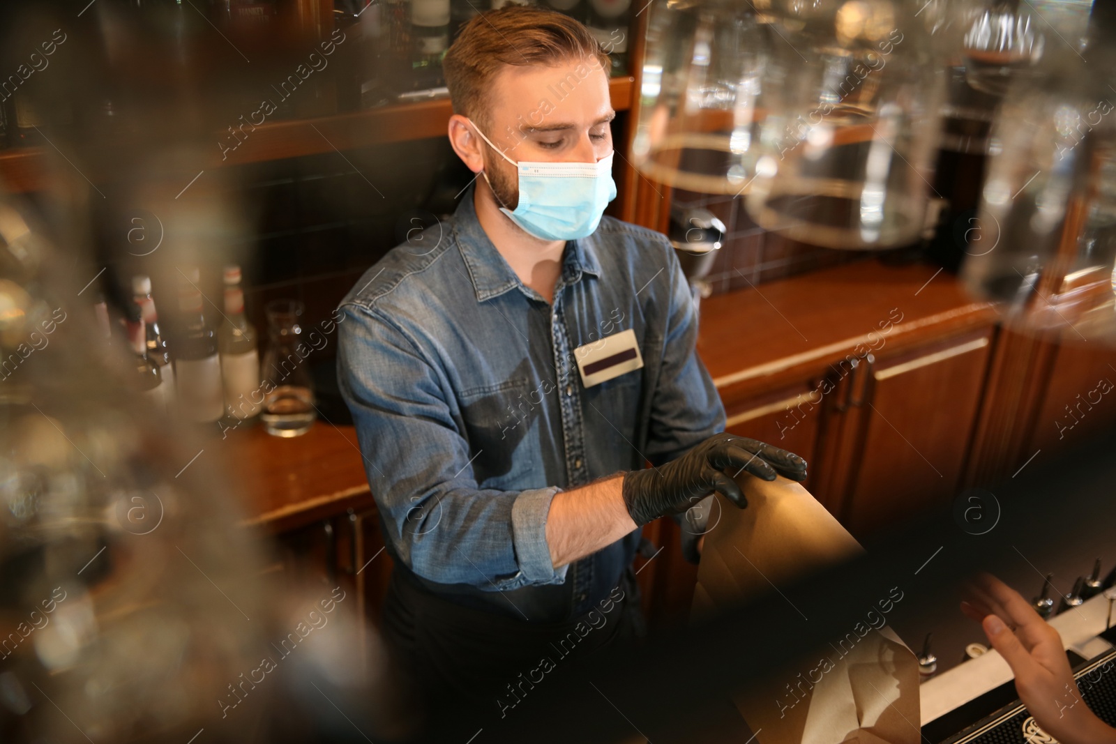 Photo of Waiter giving packed takeout order to customer in restaurant. Food service during coronavirus quarantine