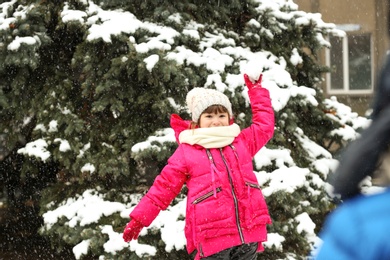 Happy children playing with snow near fir tree on winter day