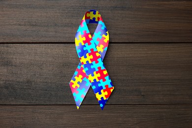 Image of World Autism Awareness Day. Colorful puzzle ribbon on wooden background, top view