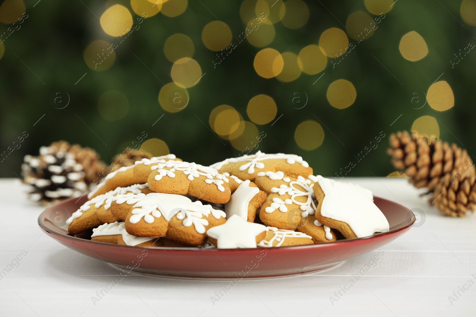 Photo of Decorated cookies on white against blurred Christmas lights