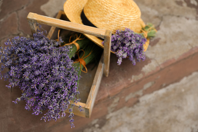 Beautiful lavender flowers and straw hat on cement floor outdoors