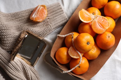 Photo of Paper box with fresh ripe tangerines and decor on white cloth, flat lay