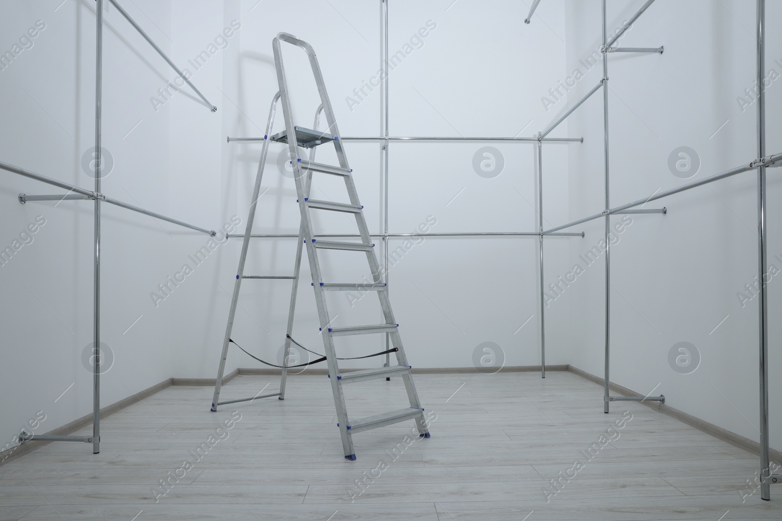 Photo of Ladder and metal pipes in empty renovated room