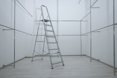 Photo of Ladder and metal pipes in empty renovated room