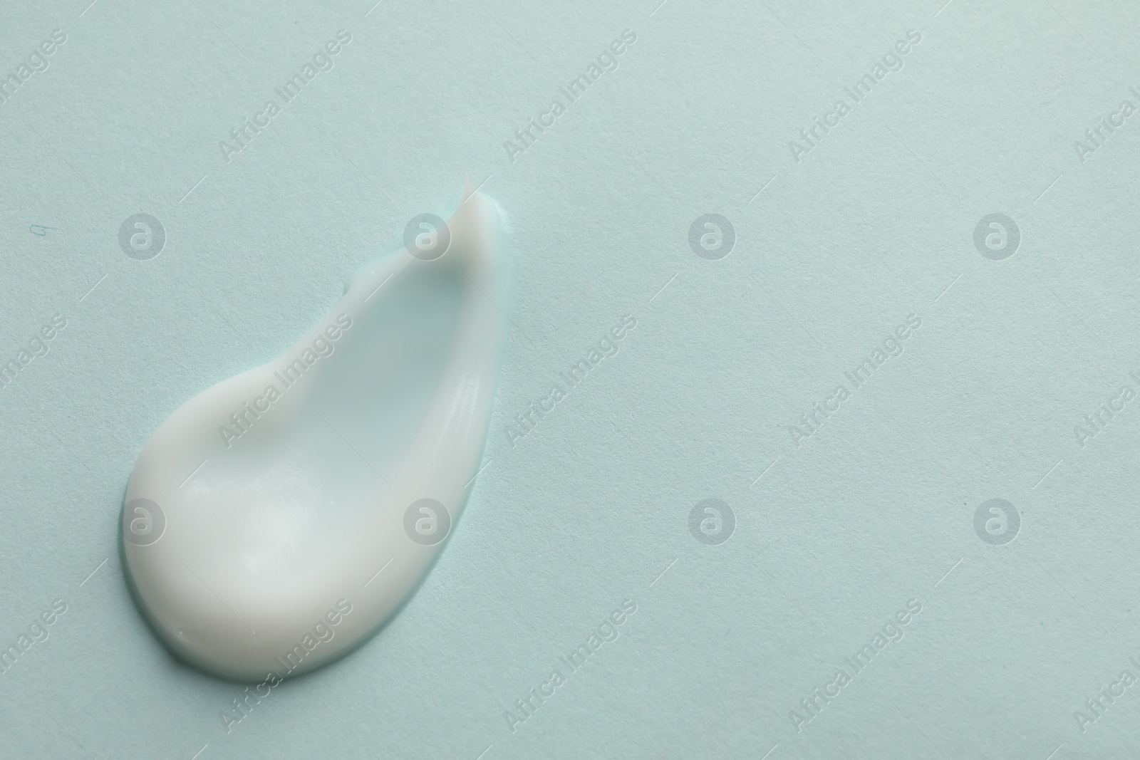 Photo of Sample of face cream on light blue background, top view. Space for text