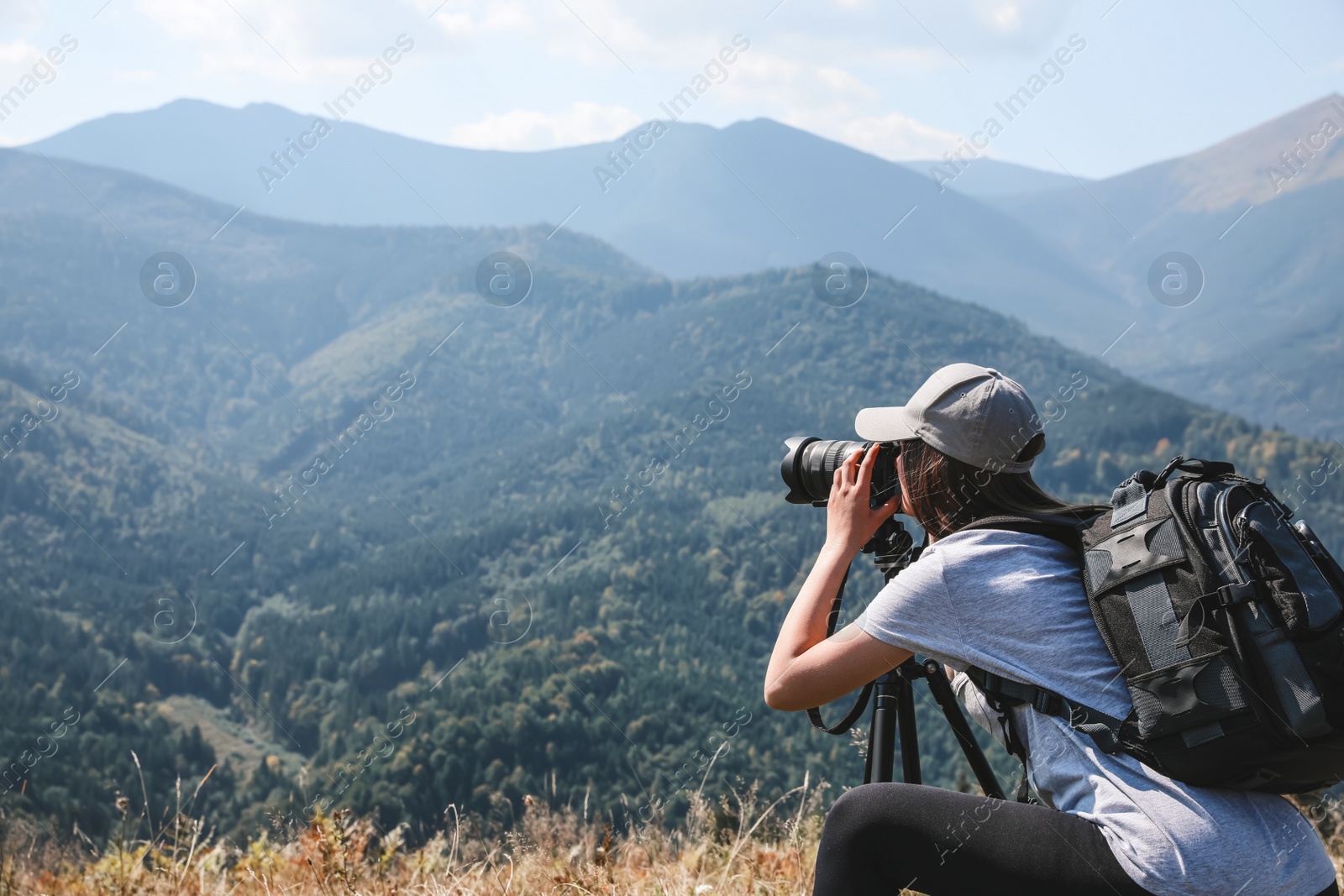 Photo of Professional photographer taking picture with modern camera in mountains. Space for text