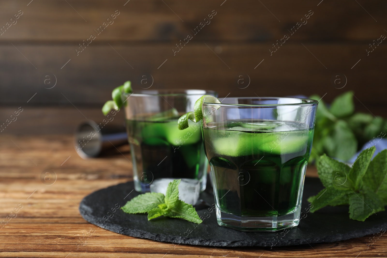 Photo of Delicious mint liqueur with green leaves on wooden table. Space for text